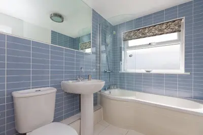 a blue tiled bathroom with a toilet and a sink at Atlantic Blue in Carbis Bay