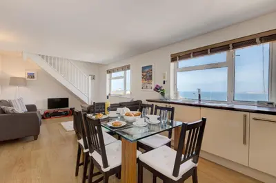 a dining room and living room with a table and chairs at Atlantic Blue in Carbis Bay