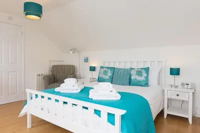 a bedroom with a white bed with towels on it at Atlantic Blue in Carbis Bay