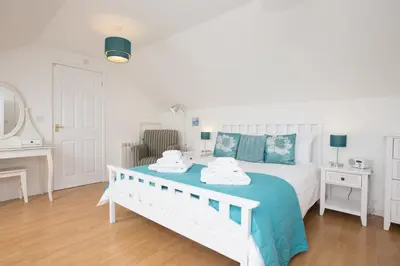 a bedroom with a large white bed with blue sheets at Atlantic Blue in Carbis Bay