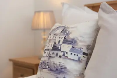 a pillow with a picture of a house on a bed at Hebaska in Carbis Bay