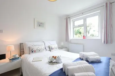 a white bedroom with a bed with towels on it at St Ives Bay View in Carbis Bay
