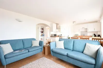 a living room with two blue couches and a kitchen at St Ives Bay View in Carbis Bay