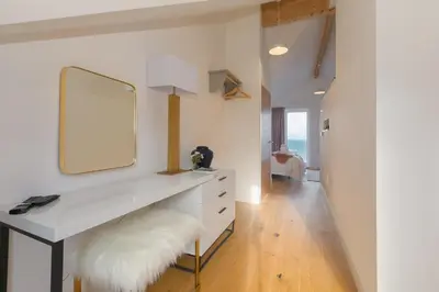 a white dressing table with a mirror and a white stool at Beach View in St Ives