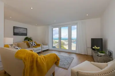 a living room with white furniture and a view of the ocean at Beach View in St Ives