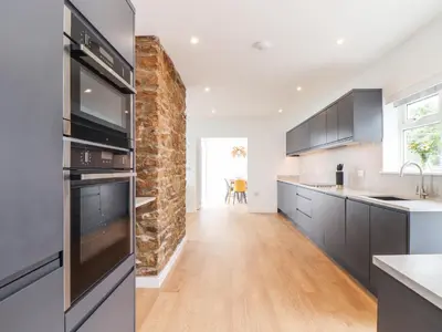 a kitchen with black appliances and a brick wall at Boscregan in Helston