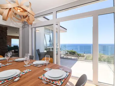a dining room with a table with a view of the ocean at Boscregan in Helston