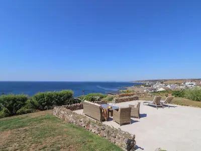 a patio with chairs and a table and the ocean at Boscregan in Helston
