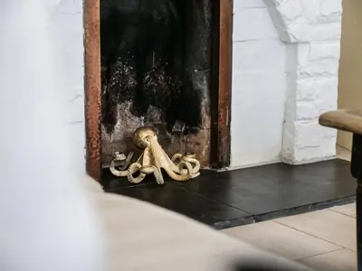 a skeleton sitting on a floor next to a painting at Padstow Escapes - Captains Cottage in Padstow
