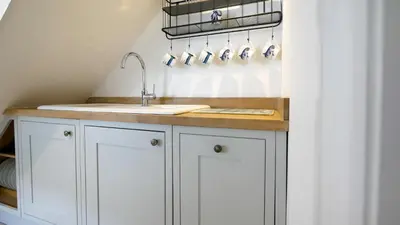 a kitchen with white cabinets and a sink at Padstow Escapes - Captains Cottage in Padstow