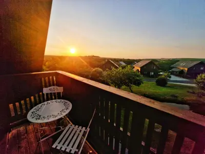 a balcony with a table and chairs and the sunset at Lake View Lodge in Saint Columb Major