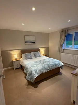 a bedroom with a large bed and two night stands at Lake View Lodge in Saint Columb Major