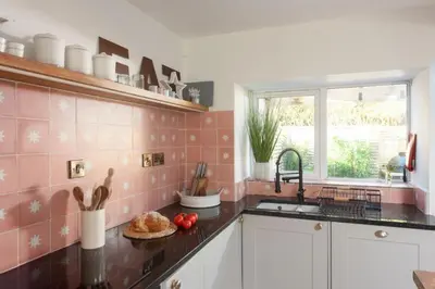 a kitchen with pink tile on the wall and a sink at Maris Cottage in St. Agnes