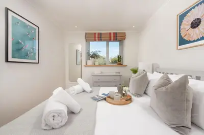 a white bedroom with a large white bed with pillows at Maris Cottage in St. Agnes