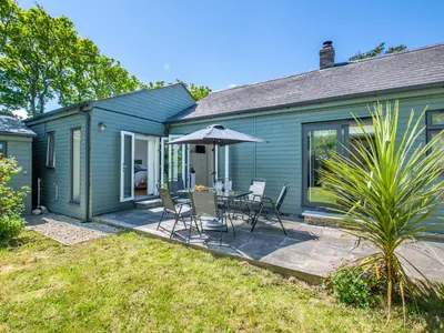 a blue house with a patio with a table and an umbrella at Bay Tree in Crackington Haven
