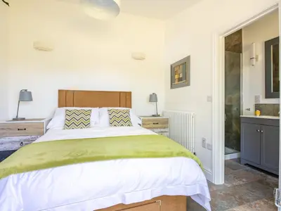 a bedroom with a large bed and a bathroom at Bay Tree in Crackington Haven