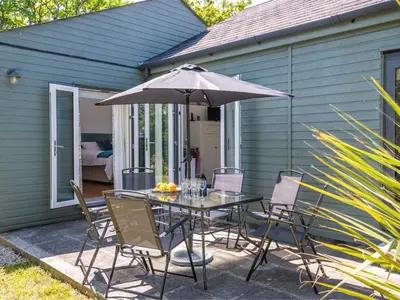 a table and chairs with an umbrella on a patio at Bay Tree in Crackington Haven