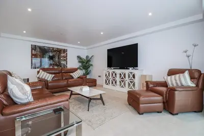 a living room with leather furniture and a flat screen tv at 13 Cliff Edge in Newquay