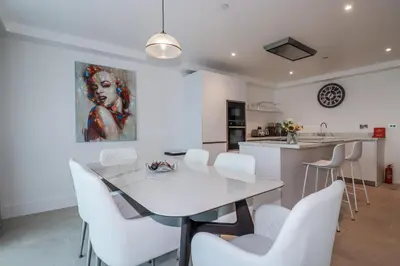 a kitchen and dining room with a white table and white chairs at 13 Cliff Edge in Newquay