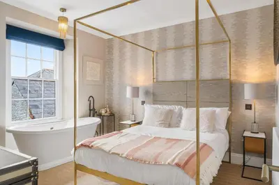 a bedroom with a bed and a bath tub and a bed and a sink at Tregurno in St Ives