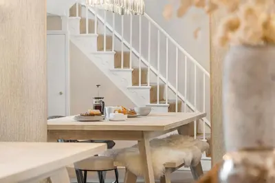 a dining room with a table and a staircase at Tregurno in St Ives
