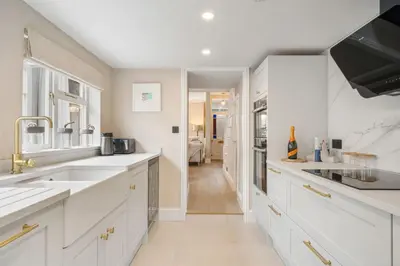 a kitchen with white cabinets and sinks and a hallway at Tregurno in St Ives