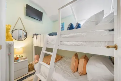 a bedroom with two bunk beds and a crib at Tregurno in St Ives