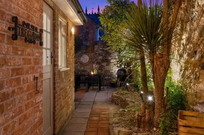 an alley with a palm tree next to a brick building at Tregurno in St Ives