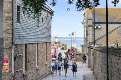 a group of people walking down a street at Tregurno in St Ives