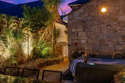 a stone building with a hot tub in a yard at Tregurno in St Ives