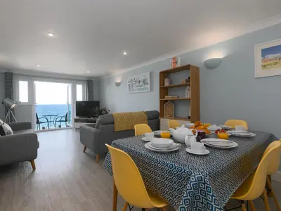 a living room with a table and chairs and the ocean at Ivory in St Ives