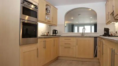 a kitchen with wooden cabinets and stainless steel appliances at Ivory in St Ives