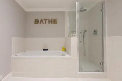 a bathroom with a tub and a shower with a bath sign at Ivory in St Ives