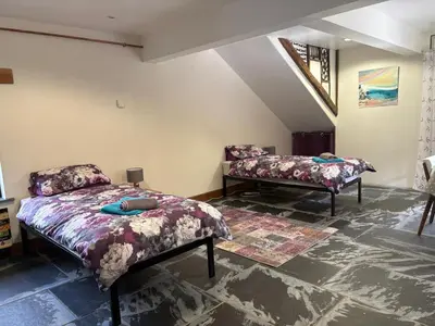 a bedroom with two beds and a bench in it at The Mill'ouse in Launceston