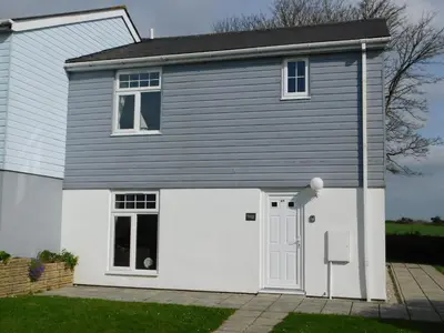 a white and grey house with a white garage at Primrose Cottage, spacious 4 bed house near Newquay in Newquay