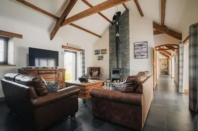 a living room with leather furniture and a fireplace at Sea View at Widemouth Bay - 3 bedroom cottage in Poundstock