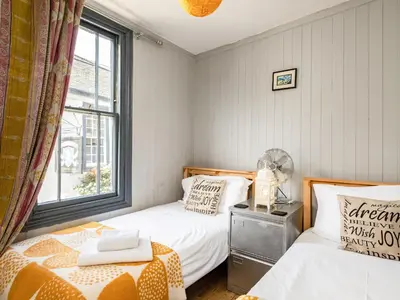 two beds in a small room with a window at Pibbies in Port Isaac