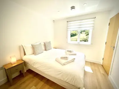 a bedroom with a white bed with a window at Trewhiddle Retreat V9 by Together Travel - Luxury 4-Bedroom Villa in St Austell