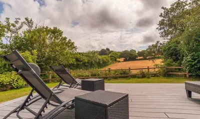 two chairs and a table on a patio at Trewhiddle Retreat V9 by Together Travel - Luxury 4-Bedroom Villa in St Austell