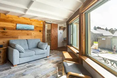 a living room with a couch and a window at The Olde Piggery, on the coast, Zennor, St Ives in Zennor