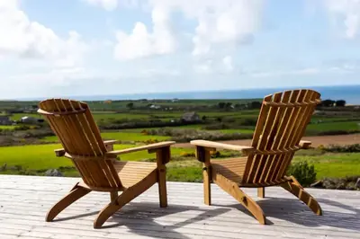 two wooden chairs sitting next to each other on a deck at The Olde Piggery, on the coast, Zennor, St Ives in Zennor