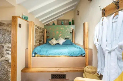 a bedroom with a bed with a blue comforter at The Olde Piggery, on the coast, Zennor, St Ives in Zennor