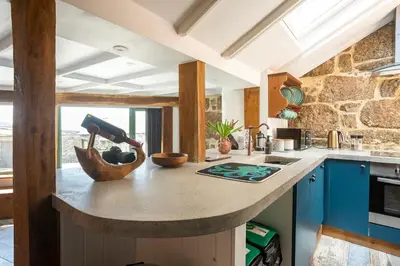 a kitchen with a large island in a kitchen with blue cabinets at The Olde Piggery, on the coast, Zennor, St Ives in Zennor