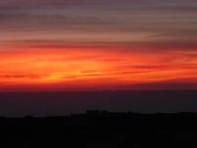 a sunset in the sky over a field at The Olde Piggery, on the coast, Zennor, St Ives in Zennor