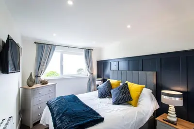 a bedroom with a bed with yellow and blue pillows at 10 Boskenza Court in Carbis Bay
