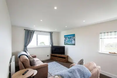 a living room with two chairs and a tv at 10 Boskenza Court in Carbis Bay