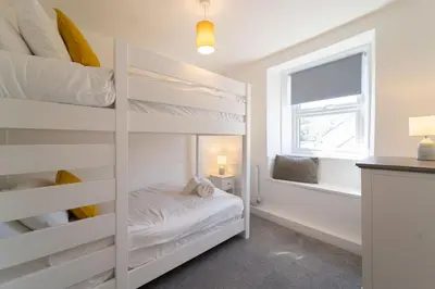 a bedroom with bunk beds and a window at Karibu - Boutique Cottage with Parking - Short walk to Beach in St Ives