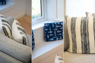 a couch with pillows sitting next to a window at Karibu - Boutique Cottage with Parking - Short walk to Beach in St Ives