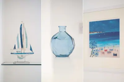 a blue glass vase on a shelf next to some pictures at Karibu - Boutique Cottage with Parking - Short walk to Beach in St Ives