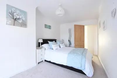 a bedroom with a white bed and a white dresser at Meledor in Marazion